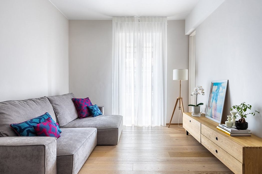 Cozy living room with plush gray couch, wooden media cabinet, and delicate curtains.