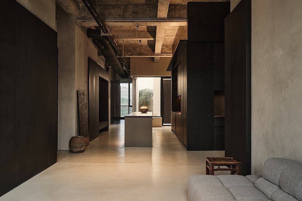 Dark, modern hallway with exposed wooden beams, concrete floors, and minimalist furnishings.