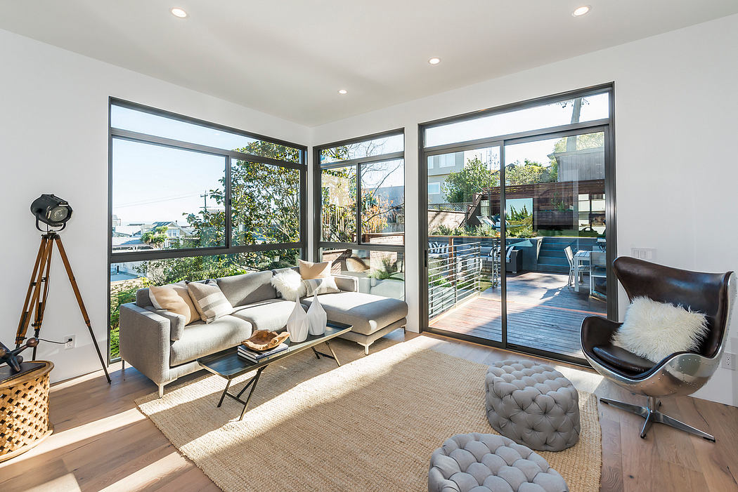 Spacious and modern living room with large windows, plush seating, and outdoor deck.