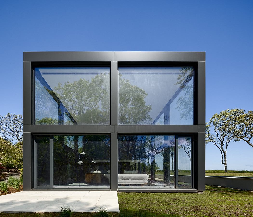 A modern glass-and-steel structure with a spacious outdoor seating area surrounded by lush greenery.