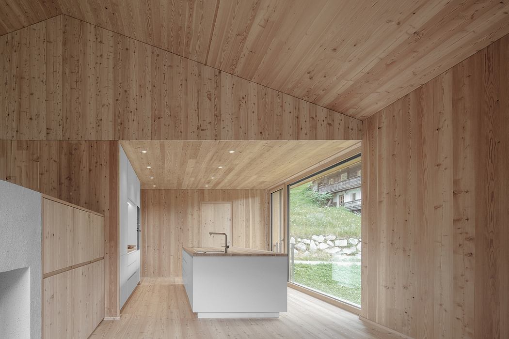 A modern, minimalist kitchen with wood-paneled walls and large windows overlooking a natural setting.