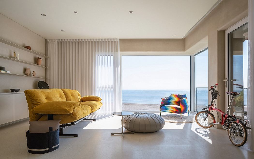 Spacious living room with floor-to-ceiling windows overlooking the ocean, modern furnishings.