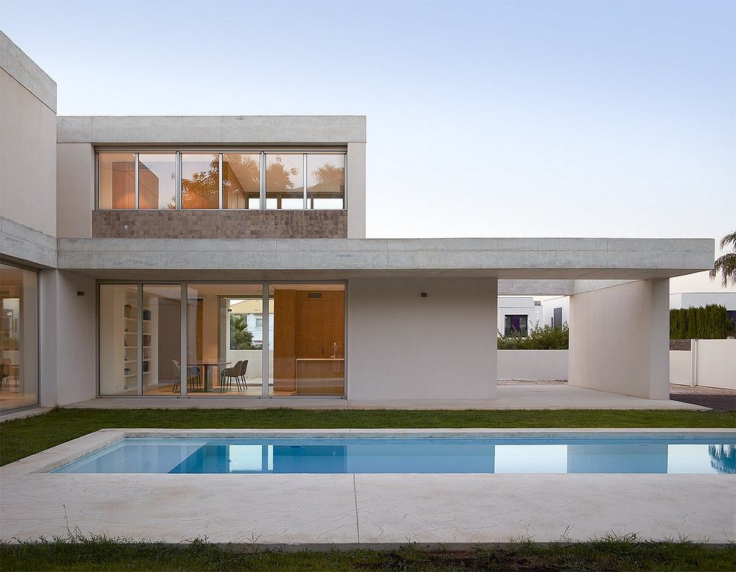 A modern, minimalist house with a rectangular design, large windows, and a pool.