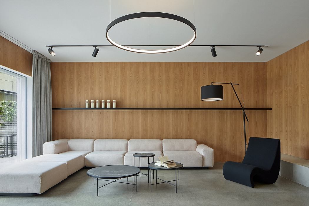 Minimalist living room with wooden walls, circular lighting fixture, and modern furniture.