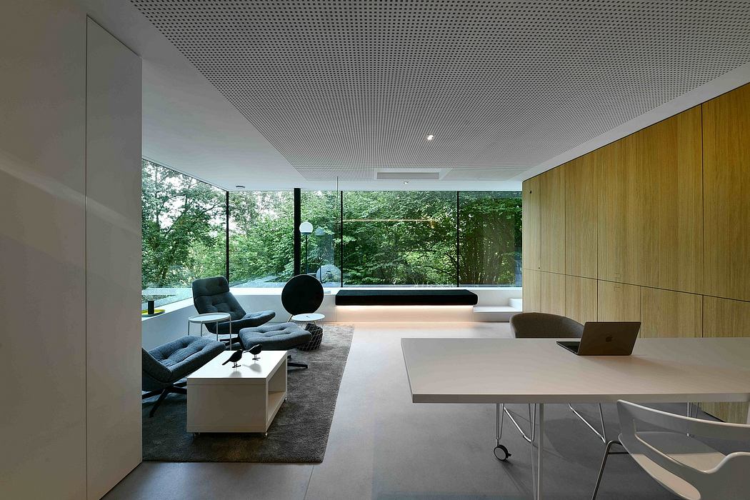 Minimalist open-plan living space with floor-to-ceiling windows, wood paneling, and modern furniture.