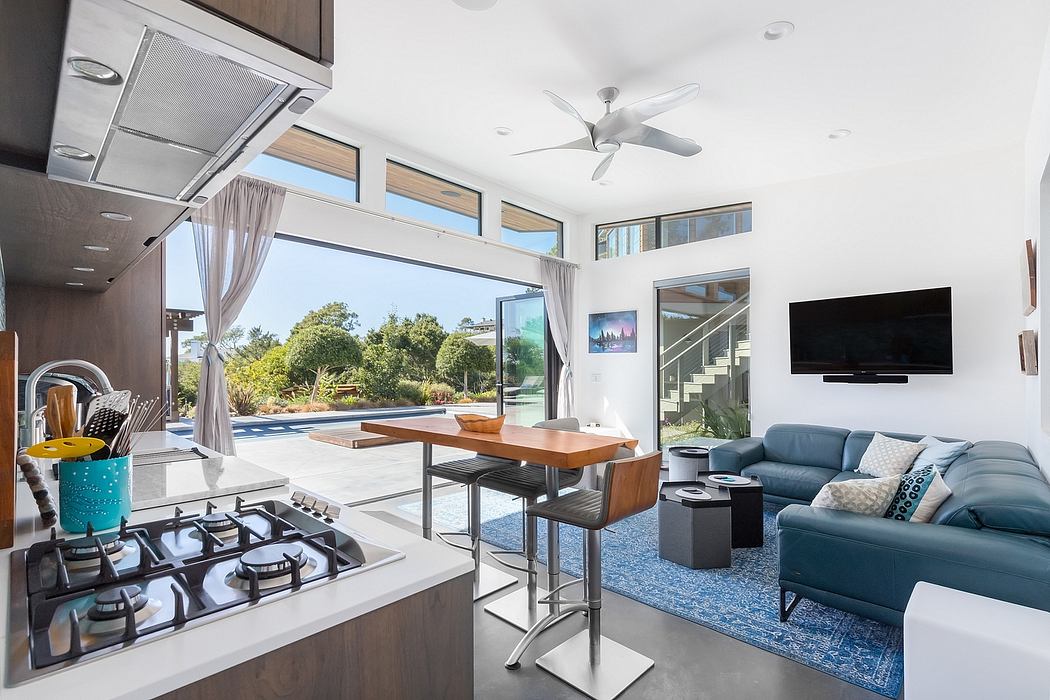 Modern open-concept living space with kitchen, dining area, and living room overlooking an outdoor pool.