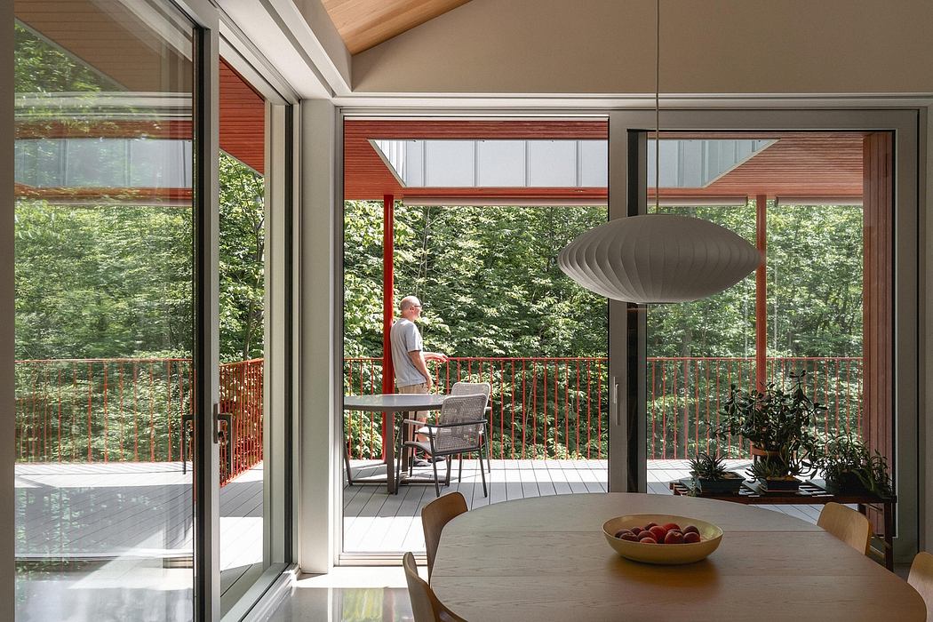 A modern, open-plan interior with expansive windows, wooden accents, and a suspended light fixture.