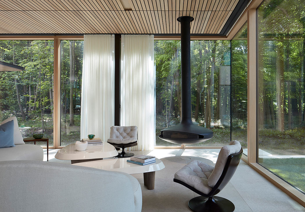 Spacious contemporary living room with floor-to-ceiling windows, modern furnishings, and natural surroundings.