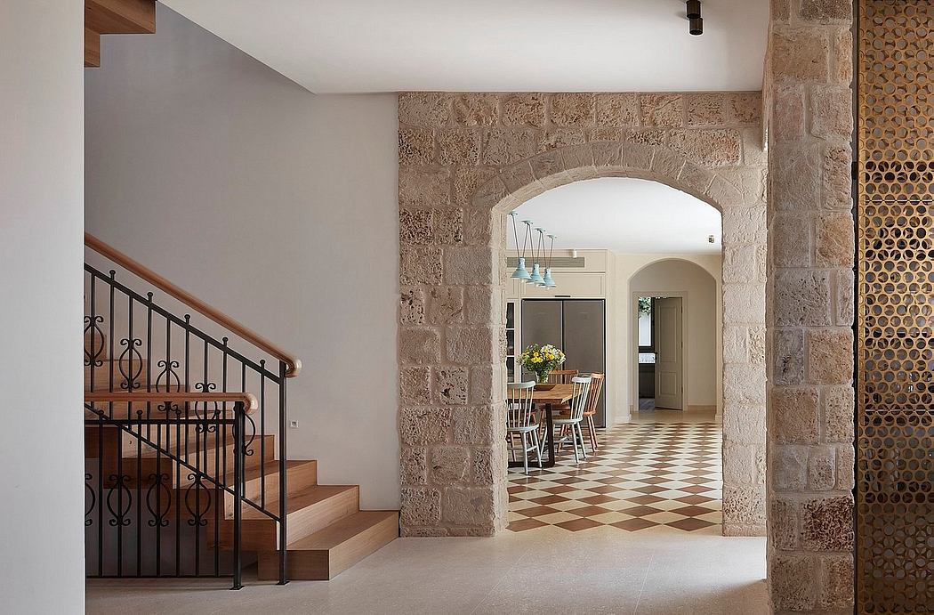 Spacious entryway with arched stone walls, wood stairs, and patterned tile flooring.