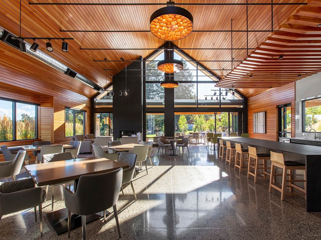 A warm, modern interior with wooden ceilings, hanging lamps, and expansive windows.