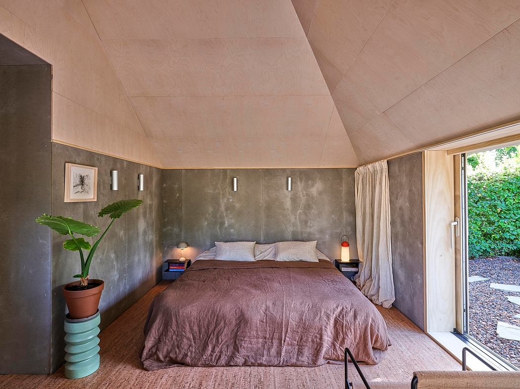 Minimalist bedroom with concrete walls, wooden floors, and modern furnishings. Sliding glass doors lead to outdoor patio.