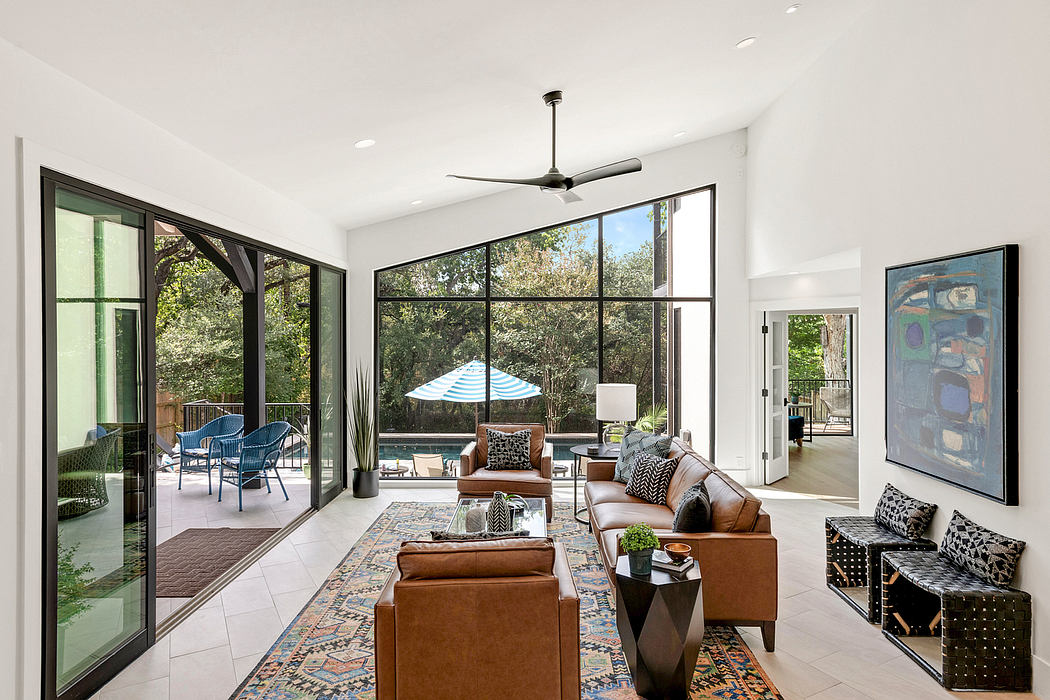 Spacious, modern living room with large windows, patterned rug, and outdoor seating area.