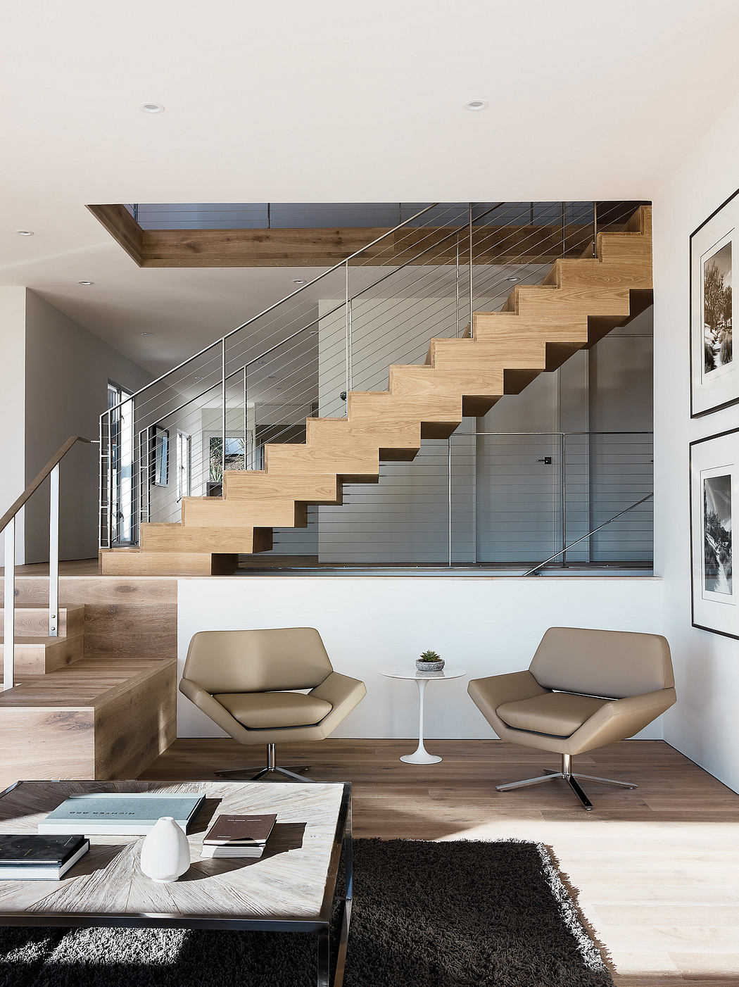 Sleek and modern staircase with wooden steps and metal railing, accented by neutral-toned furniture.