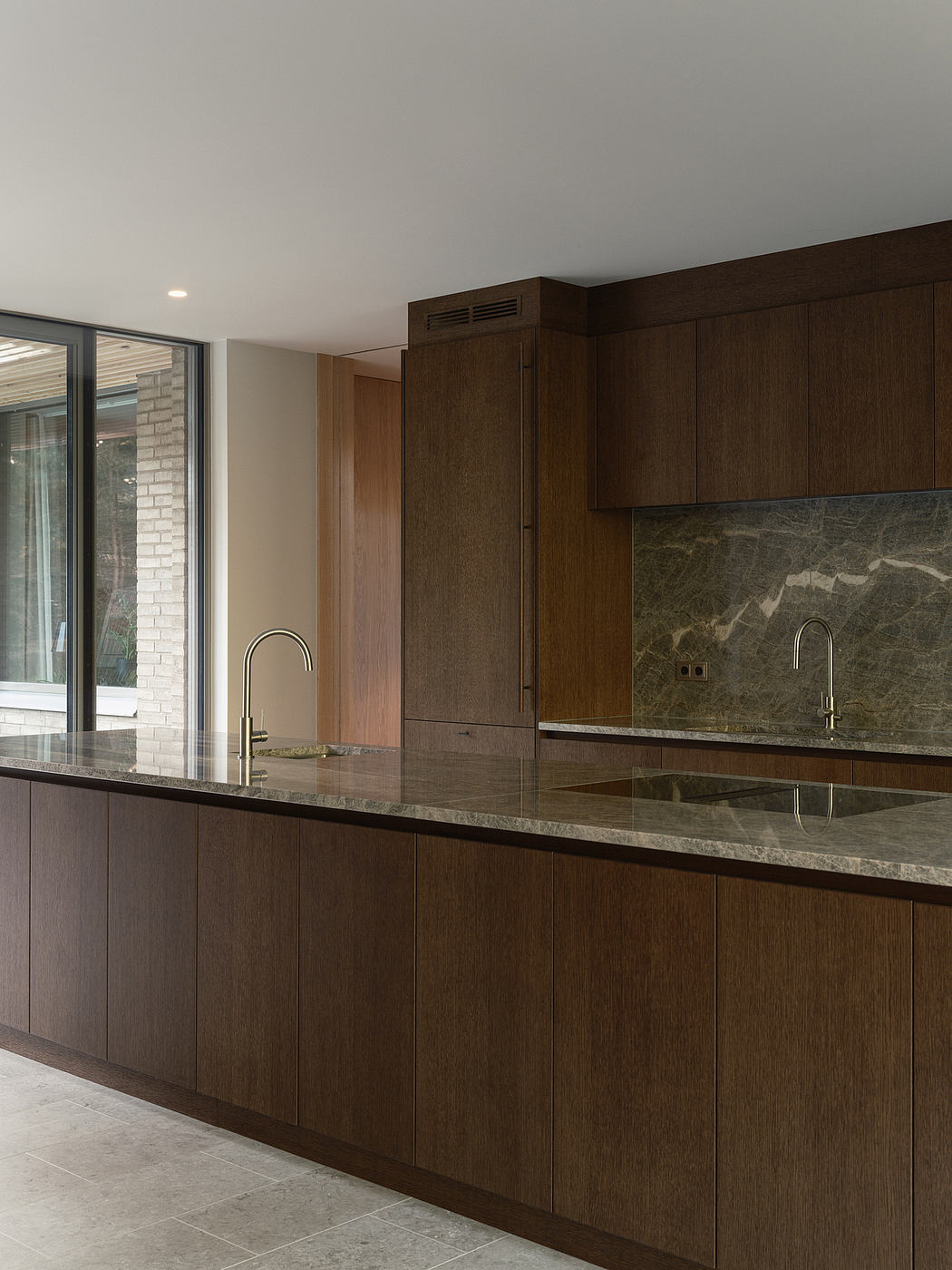 Sleek, modern kitchen with dark wood cabinetry, stone countertops, and large windows.
