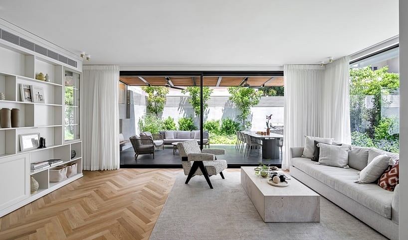 Spacious living room with minimalist furniture, herringbone wood flooring, and garden view.