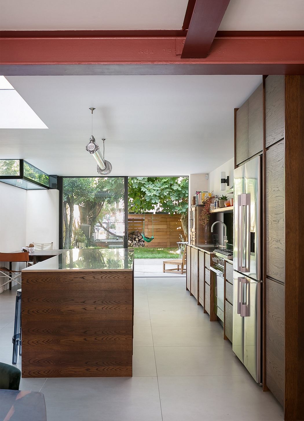 Modern kitchen with wooden cabinetry, glass windows, and natural greenery outside.