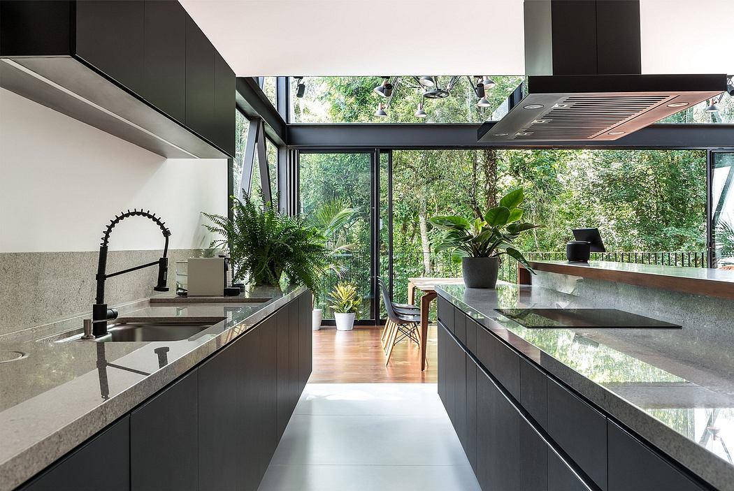 A modern kitchen with sleek black cabinetry, stone countertops, and expansive windows overlooking lush greenery.