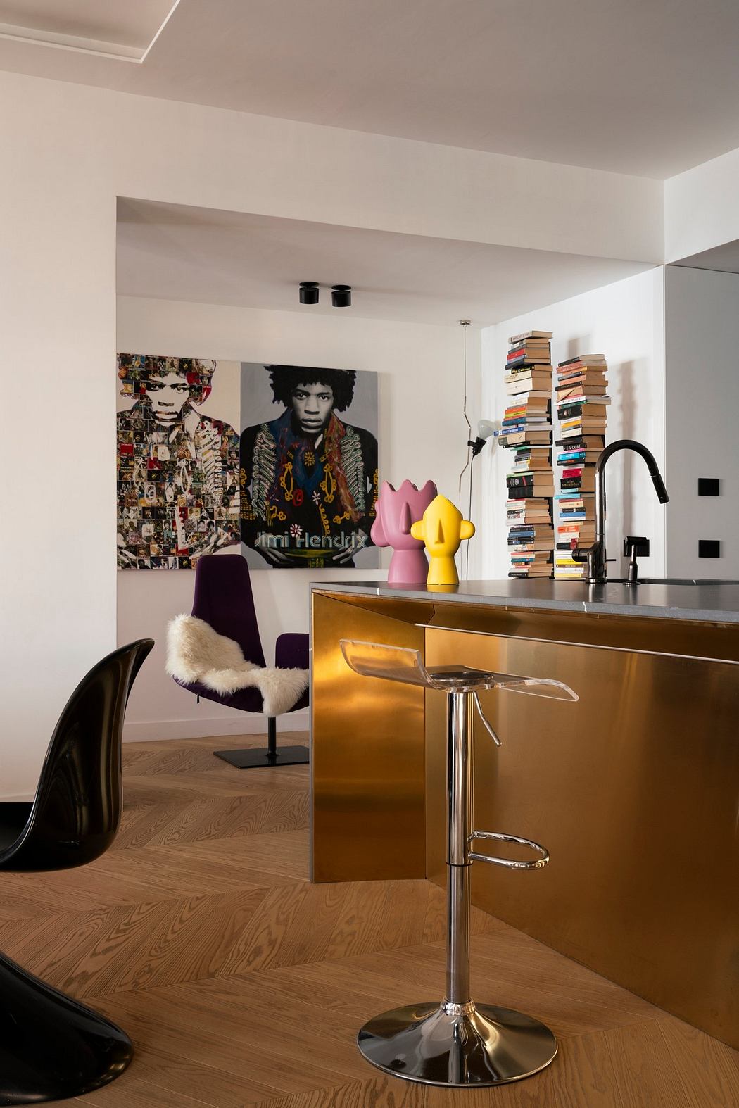 Modern, art-filled open-concept kitchen with a sleek gold bar counter and eclectic decor.