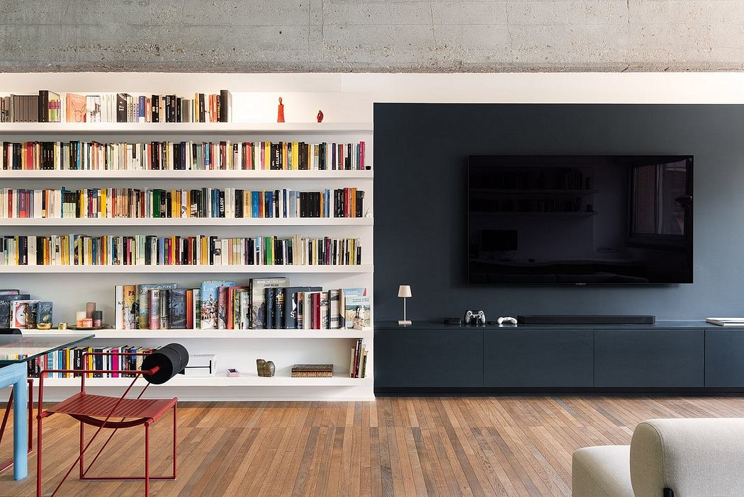 Modern living room with extensive built-in bookshelves, dark media console, and hardwood floors.