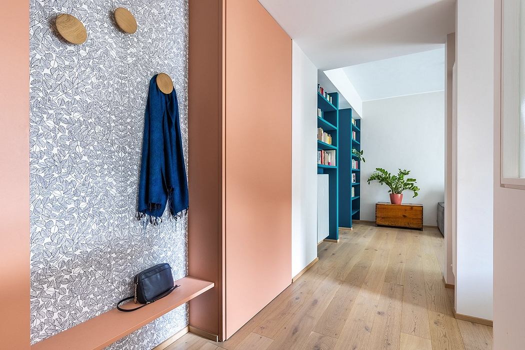 Well-designed entryway with patterned wallpaper, wood floor, and blue shelves leading to a bright hallway.