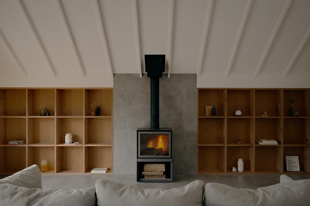 A modern, minimalist living space with a freestanding fireplace, built-in shelving, and a vaulted ceiling.
