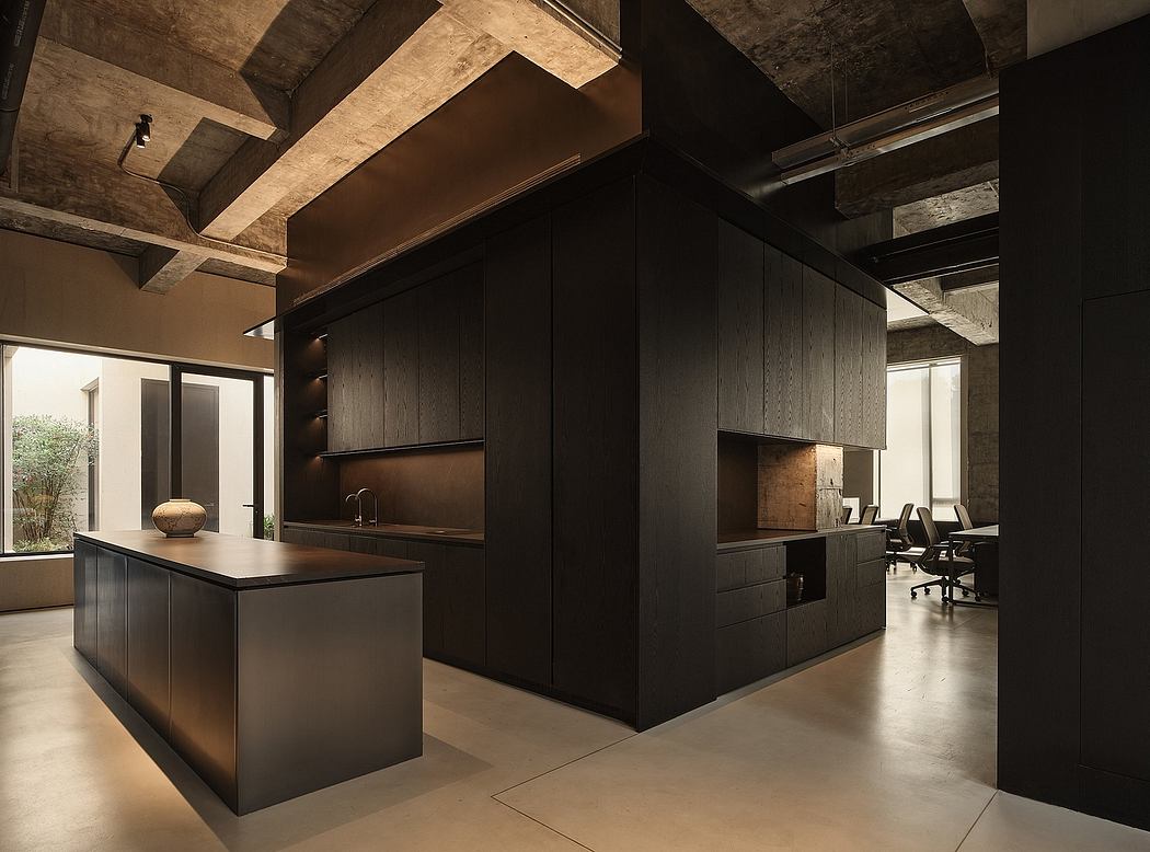 A modern, open-concept kitchen with sleek black cabinetry, concrete beams, and glass walls.