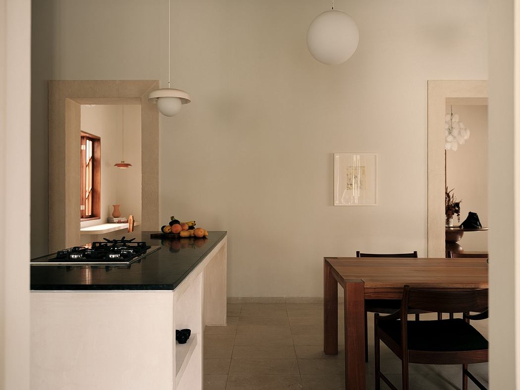 Sleek, minimalist kitchen and dining area with neutral tones, pendant lighting, and wooden furnishings.