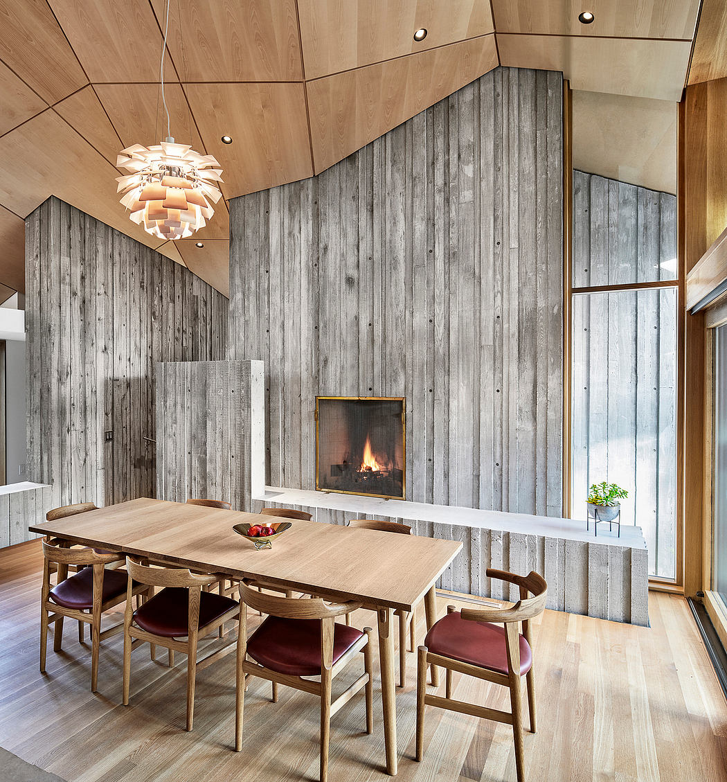 Rustic dining room with wooden walls, fireplace, and intricate lighting fixture.