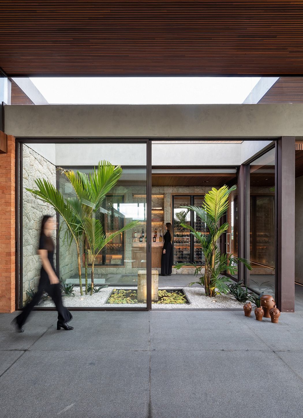 Elegant glass entryway with tropical plants, stone accents, and a wine display.