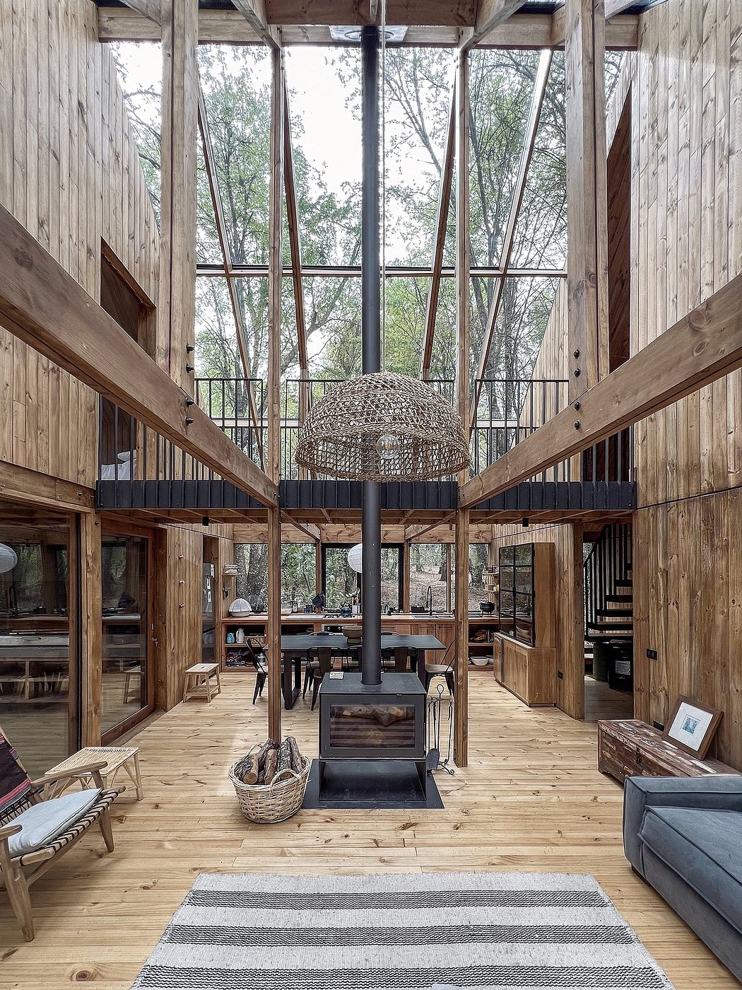 A cozy wooden cabin with a striking central fireplace and expansive glass walls.