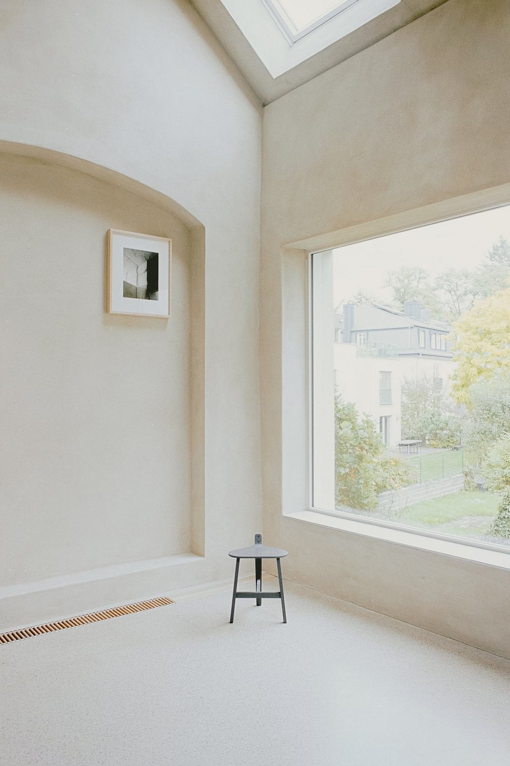 Minimalist room with high ceilings, large window, and simple, modern decor.