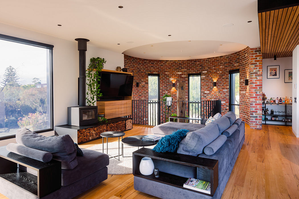 Spacious living room with brick walls, wood floors, and a cozy fireplace. Stylish decor.