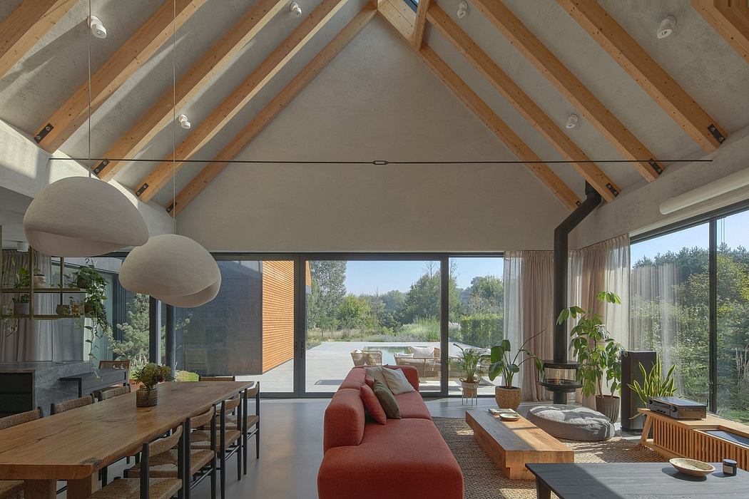An open-concept living area with a vaulted ceiling, wooden beams, and floor-to-ceiling glass windows.