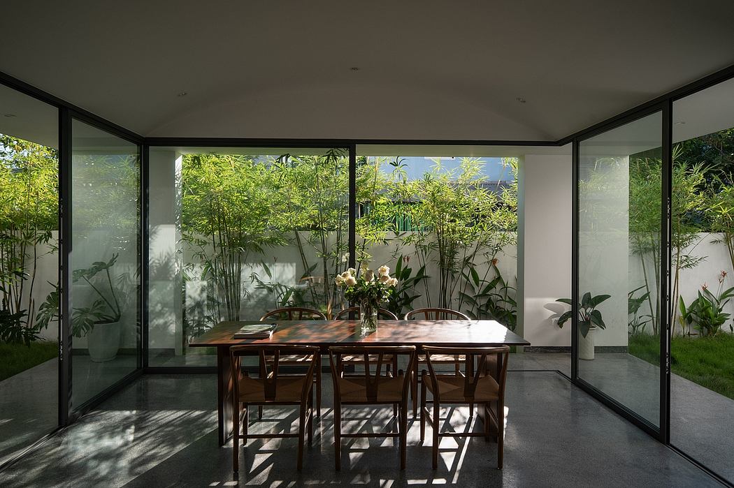 Sleek modern dining room with floor-to-ceiling windows overlooking lush greenery.