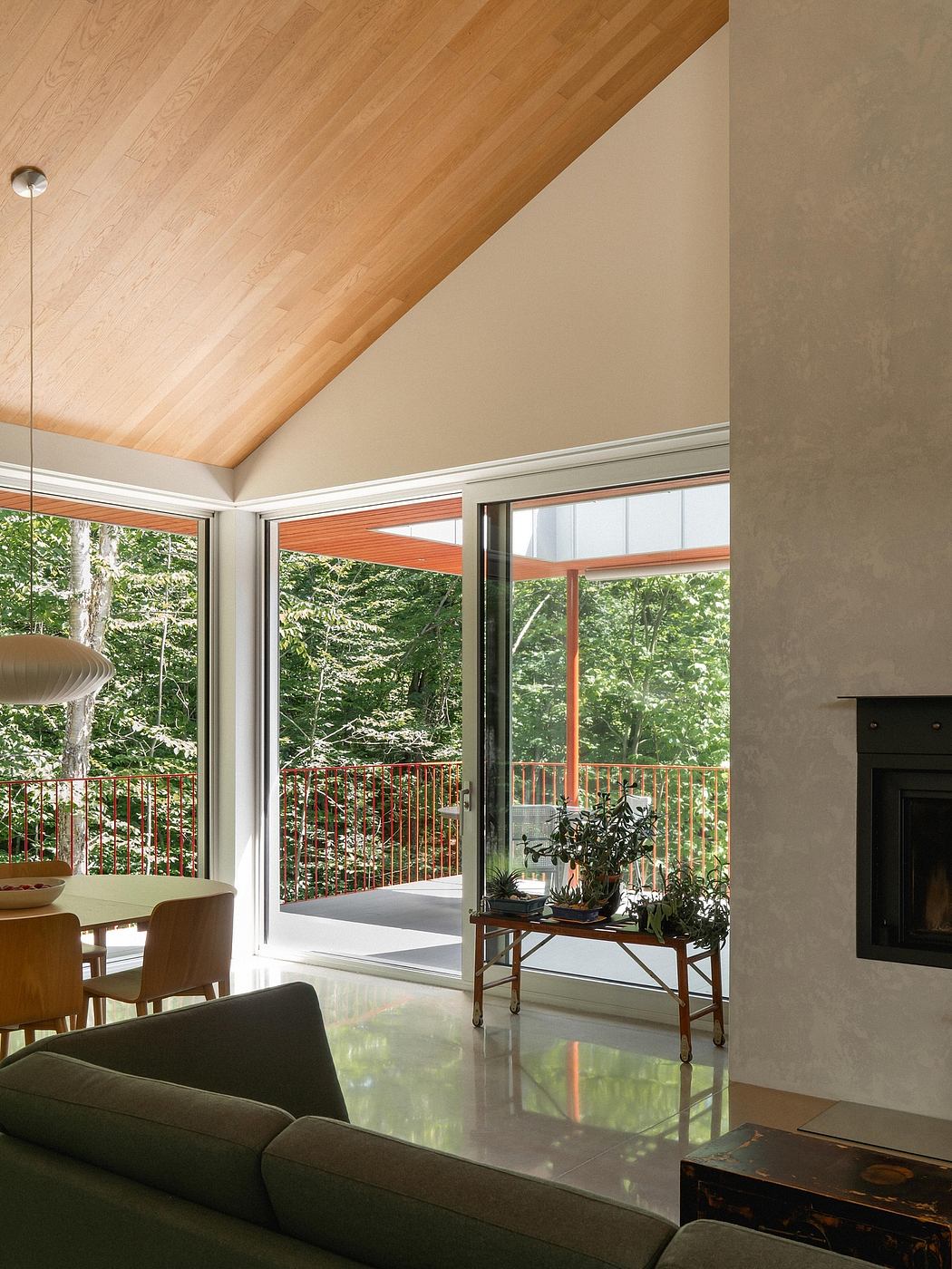 Warm wood ceiling contrasts with sleek glass walls overlooking lush greenery.
