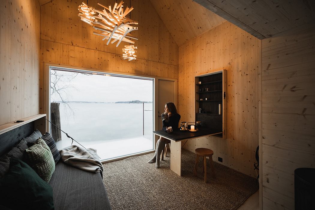 Cozy wooden cabin interior with panoramic lakeside view and modern light fixture.