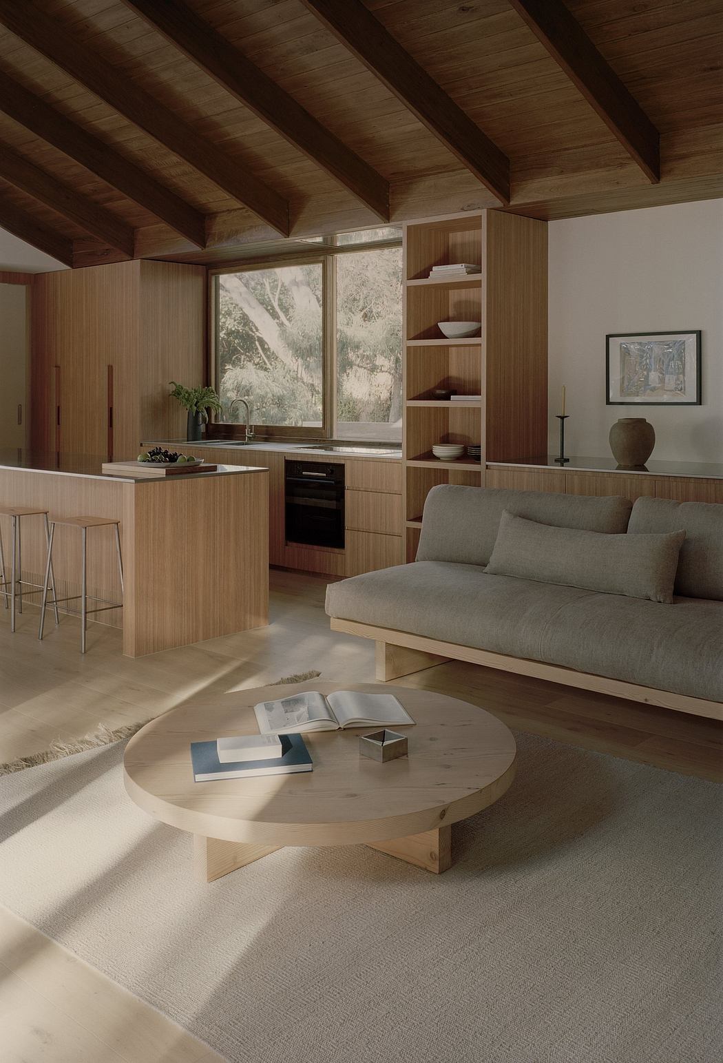 A cozy modern cabin interior with warm wood tones, sleek built-ins, and natural views.