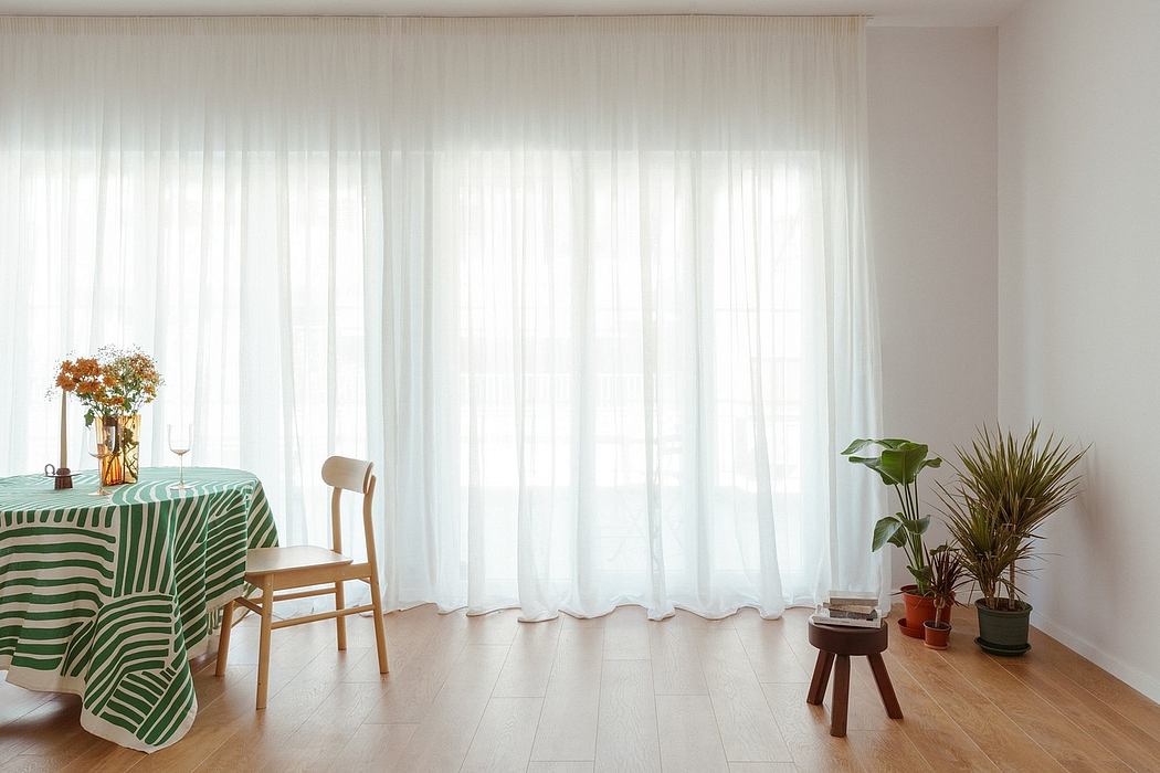 Spacious room with white curtains, striped tablecloth, and potted plants. Minimalist interior design.