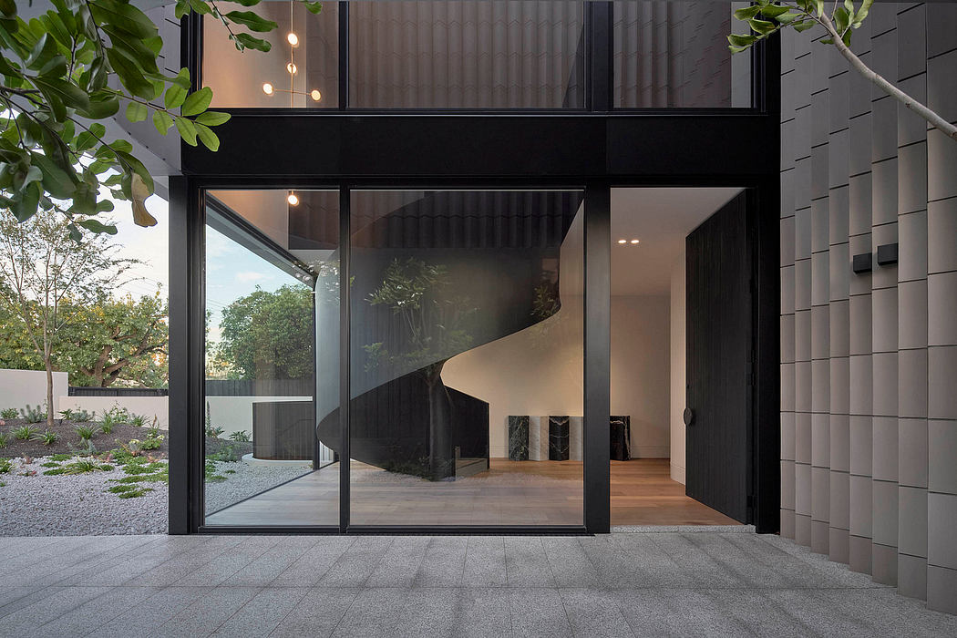 A modern, minimalist building with large glass windows, dark exterior, and greenery.