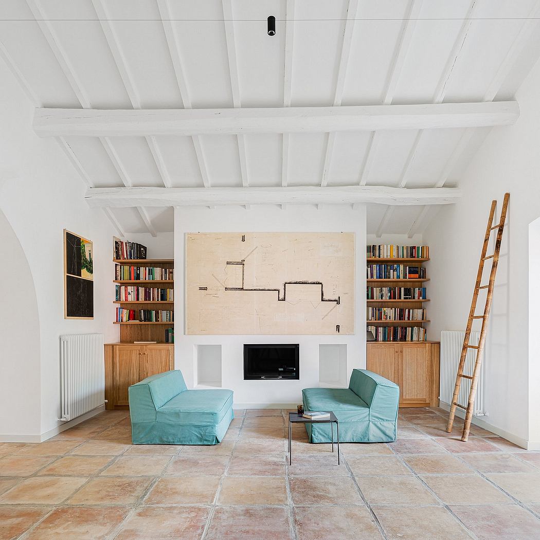 Spacious interior with exposed wooden beams, built-in bookshelves, and teal accent chairs.