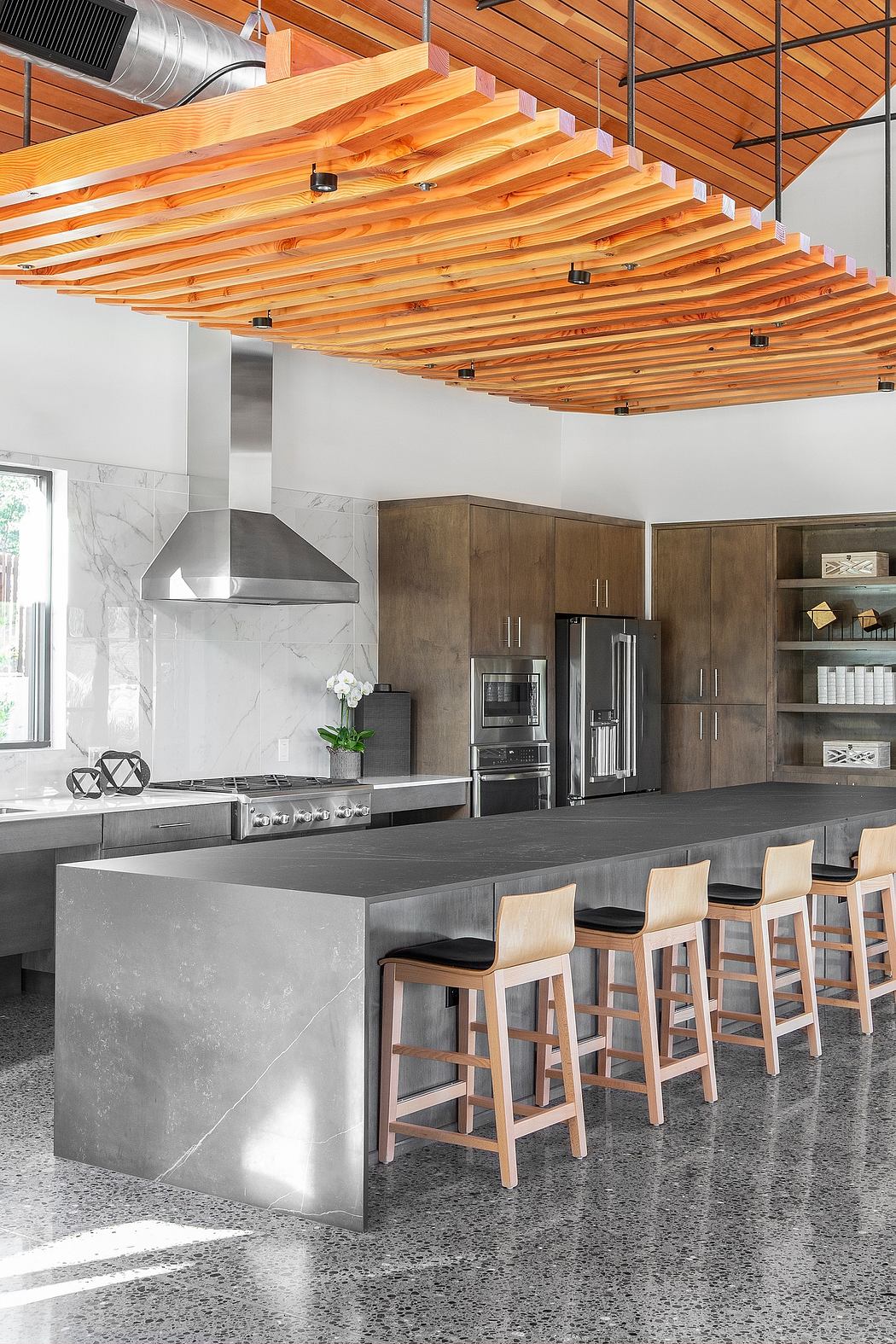 Striking modern kitchen with expansive wooden ceiling and sleek concrete counters.