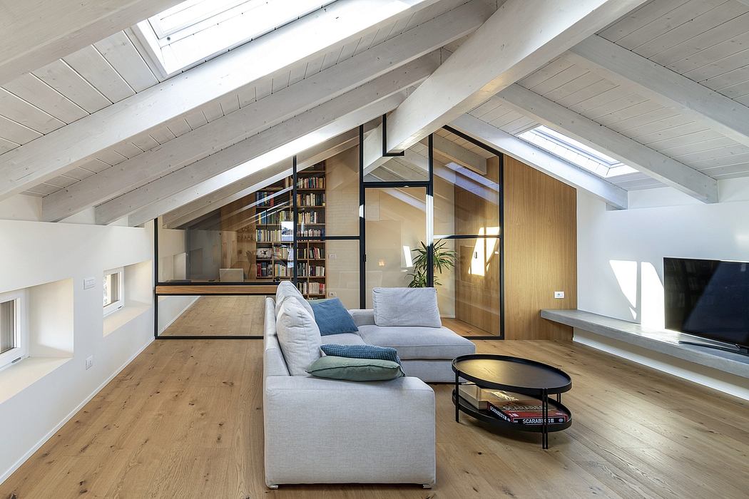 Cozy attic living space with wooden beams, built-in bookshelves, and modern furniture.