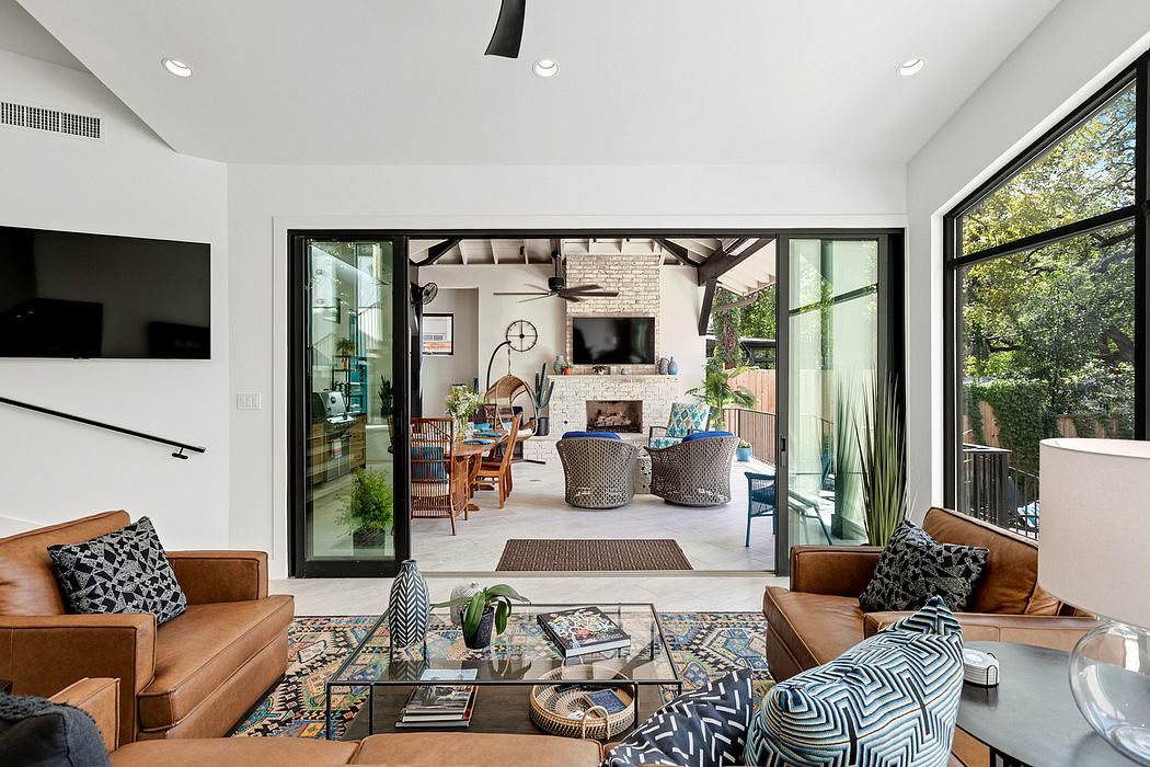 A modern, open-concept living room with large windows, a brick fireplace, and eclectic furnishings.