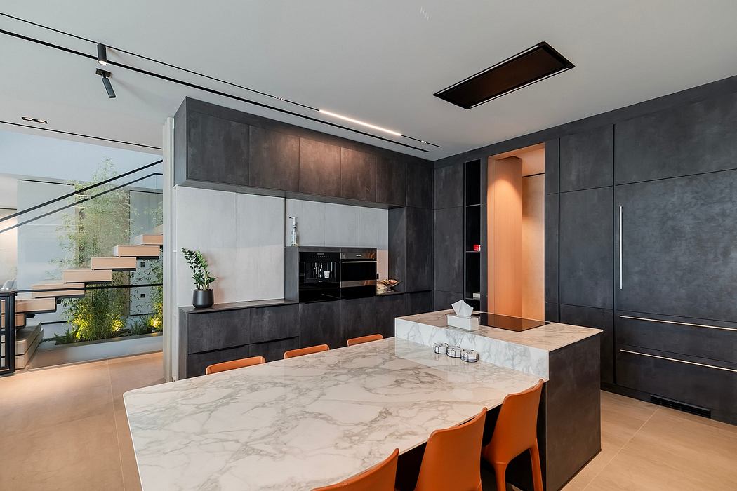 Sleek, modern kitchen with dark cabinets, marble countertop, and track lighting.