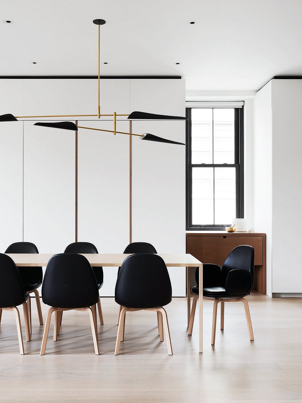Sleek, modern dining space with black chairs, wooden table, and geometric pendant lights.