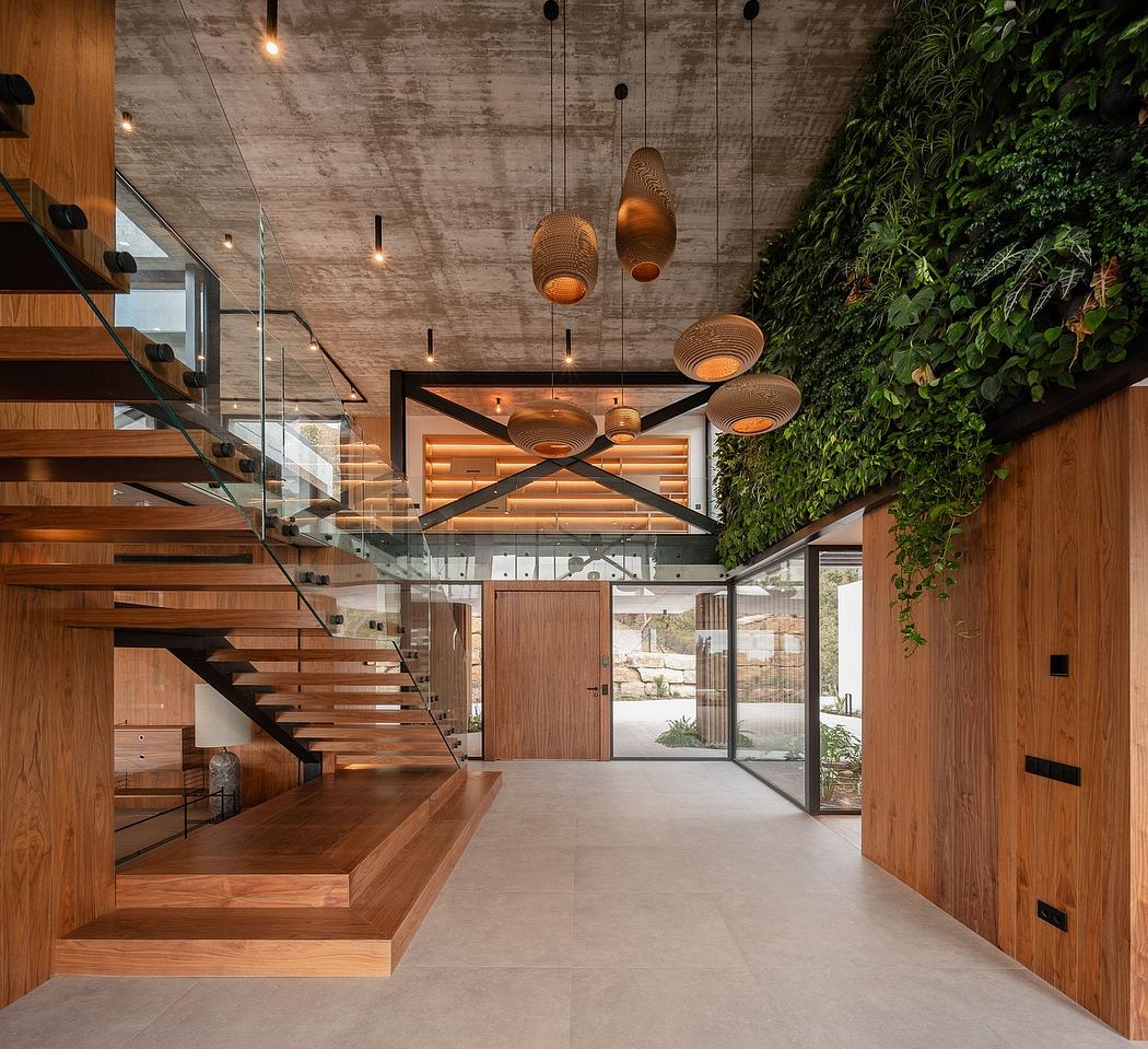 A modern interior with an open, glass-enclosed staircase, hanging light fixtures, and a living wall.