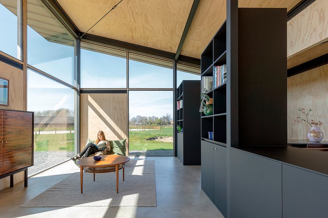 Modern and minimalist living room with floor-to-ceiling windows overlooking a pastoral scene.