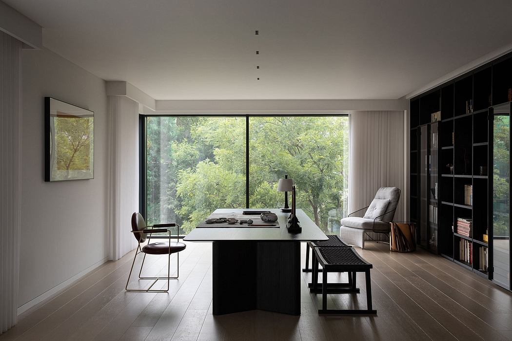 Minimalist home office with large windows, dark furniture, and nature-inspired artwork.