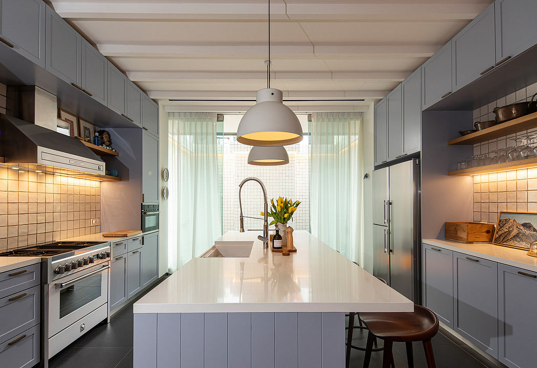 A modern kitchen with gray cabinets, a central island, and a pendant light fixture.