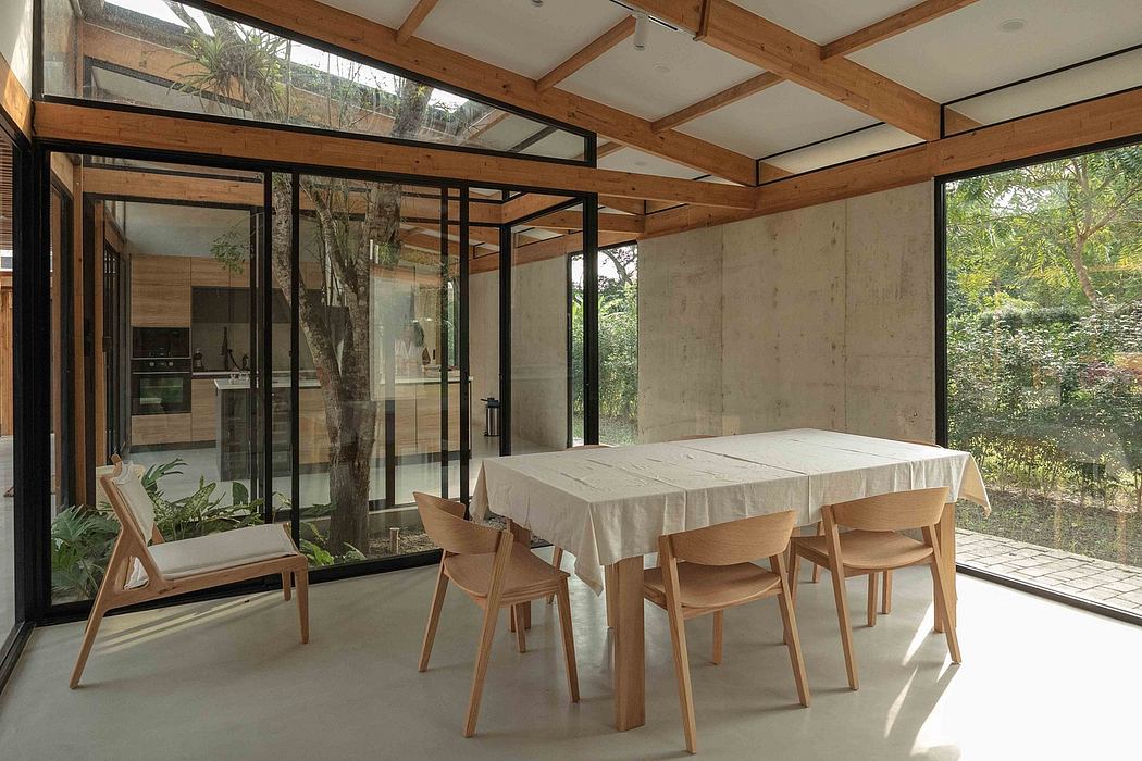 Spacious, wood-framed interior with glass walls, surrounded by lush greenery.